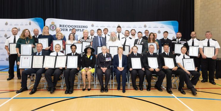 An image of officers and staff standing and sitting with certificates