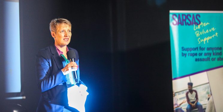 PCC Clare Moody standing on a stage, holding a mic, giving a speech.